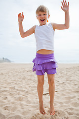 Image showing Young girl jumping in sand