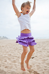 Image showing Young girl jumping in sand