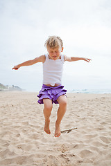 Image showing Young girl jumping in sand