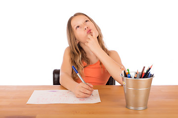 Image showing Child sitting at a table trying to make a drawing