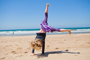 Image showing Young girl doing cartwheel at beach