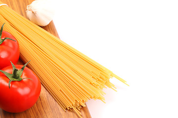 Image showing uncooked spaghetti and tomatos on a white background