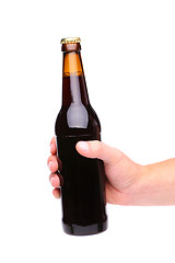 Image showing A hand holding up a brown beer bottle