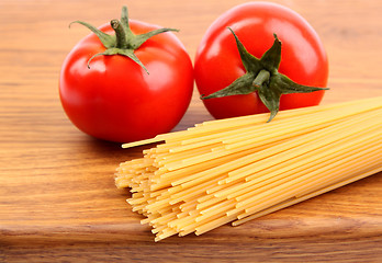 Image showing Tomatoesl and uncooked spaghetti on a cutting board