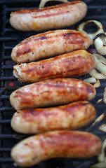 Image showing Sausages on grill with onions
