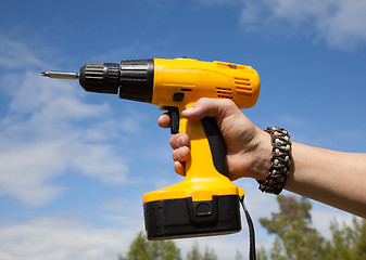 Image showing The man is holding a yellow cordless drill