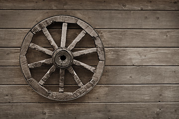 Image showing Old wagon wheel on wooden wall