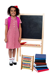 Image showing Smiling school girl standing near the blackboard