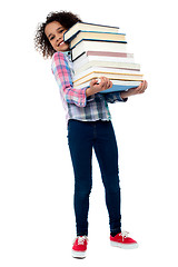 Image showing Cute cheerful child carrying stack of books