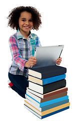 Image showing Smiling child busy with tablet pc and books