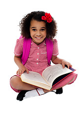 Image showing Smiling pretty school girl reading a book