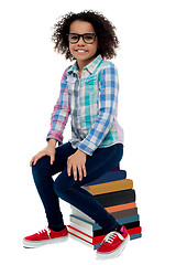 Image showing School girl sitting on stack of books