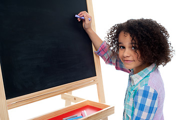 Image showing Beautiful little girl writing on classroom board