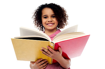 Image showing Adorable school girl reading a book with a smile