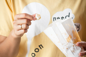 Image showing Woman eating popcorn from popcorn paper bag 