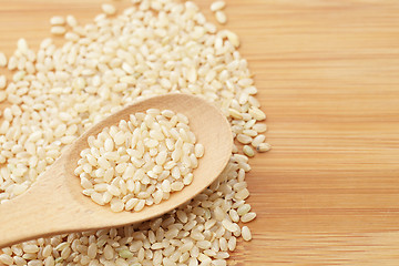 Image showing Uncooked rice on spoon over table