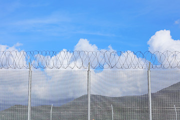 Image showing Chain link fence with barbed wire under blue sky