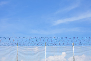 Image showing Chain link fence with barbed wire under blue sky