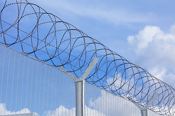 Image showing Chain link fence with barbed wire under blue sky