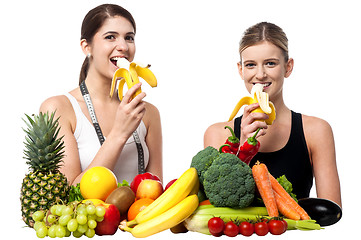 Image showing Young smiling girls eating banana