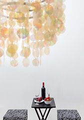 Image showing Bottle of red wine on a table, and decorative chandelier