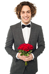 Image showing Groom in tuxedo posing with a bouquet