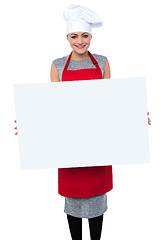 Image showing Smiling female chef holding an ad board