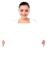 Image showing Smiling woman holding blank white ad board
