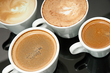 Image showing four white coffe cups on the black background