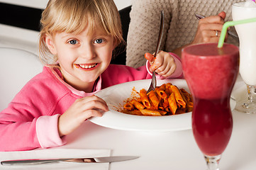 Image showing Cute kid enjoying pasta and watermelon juice