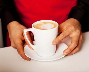 Image showing Hands of waiter serving a cup of cappucino