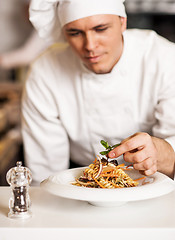 Image showing Chef decorating pasta salad with herbal leaves