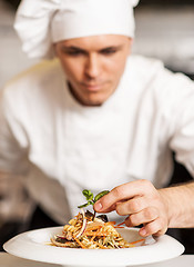 Image showing Chef decorating pasta salad with herbal leaves