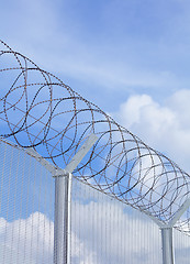 Image showing Chain link fence with barbed wire under blue sky