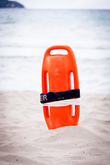 Image showing orange red life buoy in sand on beach at the sea object