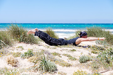 Image showing man doing pilates exercises on beach in summer