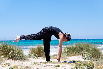 Image showing man doing pilates exercises on beach in summer