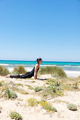 Image showing man doing pilates exercises on beach in summer