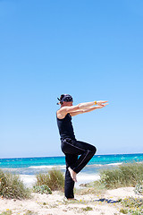 Image showing man doing pilates exercises on beach in summer