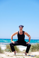 Image showing man doing pilates exercises on beach in summer