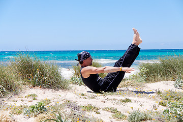 Image showing man doing pilates exercises on beach in summer