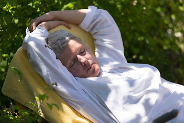 Image showing Mature woman sleeping on lounger