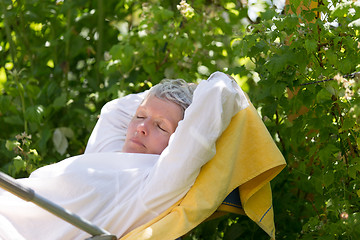Image showing Mature woman sleeping on lounger