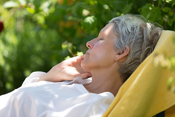 Image showing Aged woman sleeping on lounger