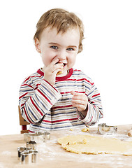 Image showing happy young child nibbling dough in white background