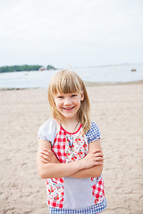 Image showing Smiling young girl at beach with arms folded