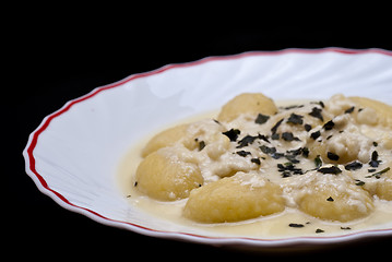 Image showing italian gnocchi with four cheese sauce isolated on black