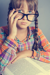 Image showing serious little girl in glasses with a book