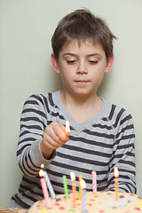 Image showing A boy lights candles on cake