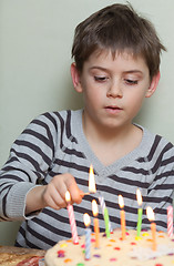 Image showing A boy lights candles on cake